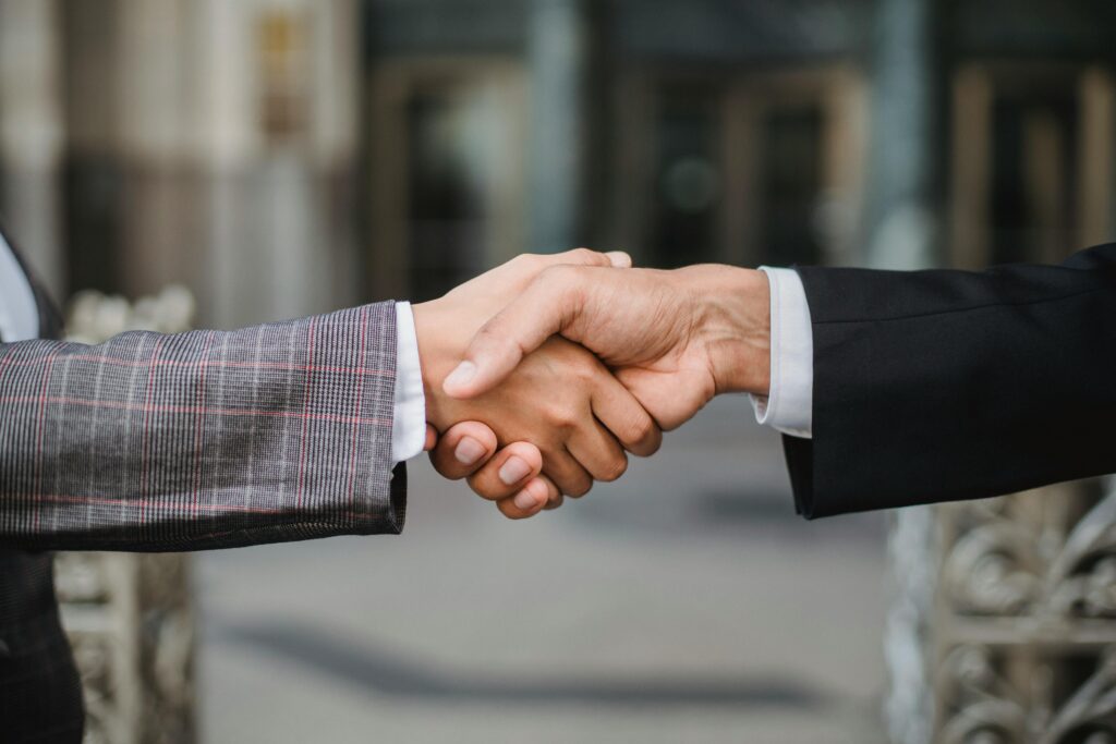 referral A close-up of two businesspeople shaking hands, symbolizing cooperation and partnership.