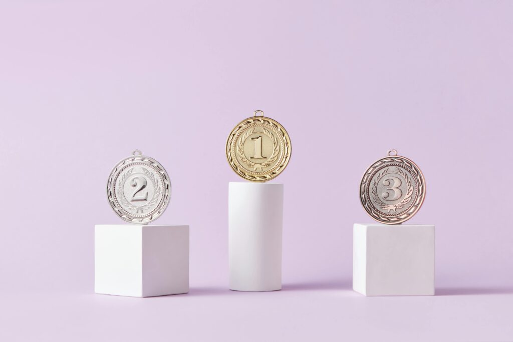 pexels-photo-7267588-7267588 Medals on a podium against a soft pastel background, ideal for awards themes.