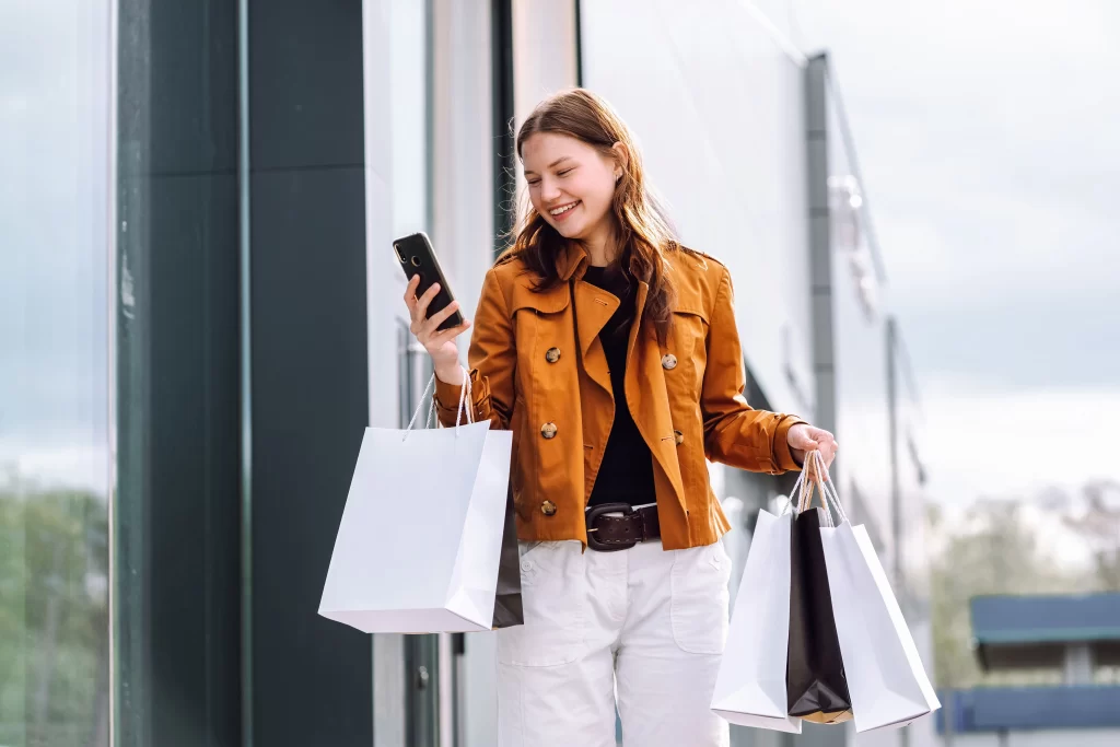 Shopper using a smartphone while carrying shopping bags to earn rewards