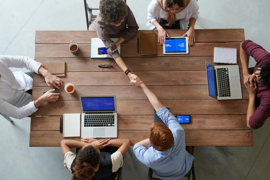 Group of people using laptops and tablets together, representing who should use passive income apps
